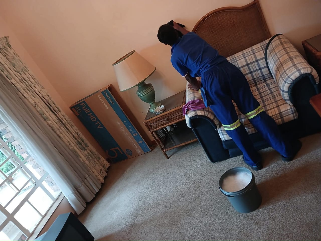 Estlas team member cleaning a checked fabric sofa